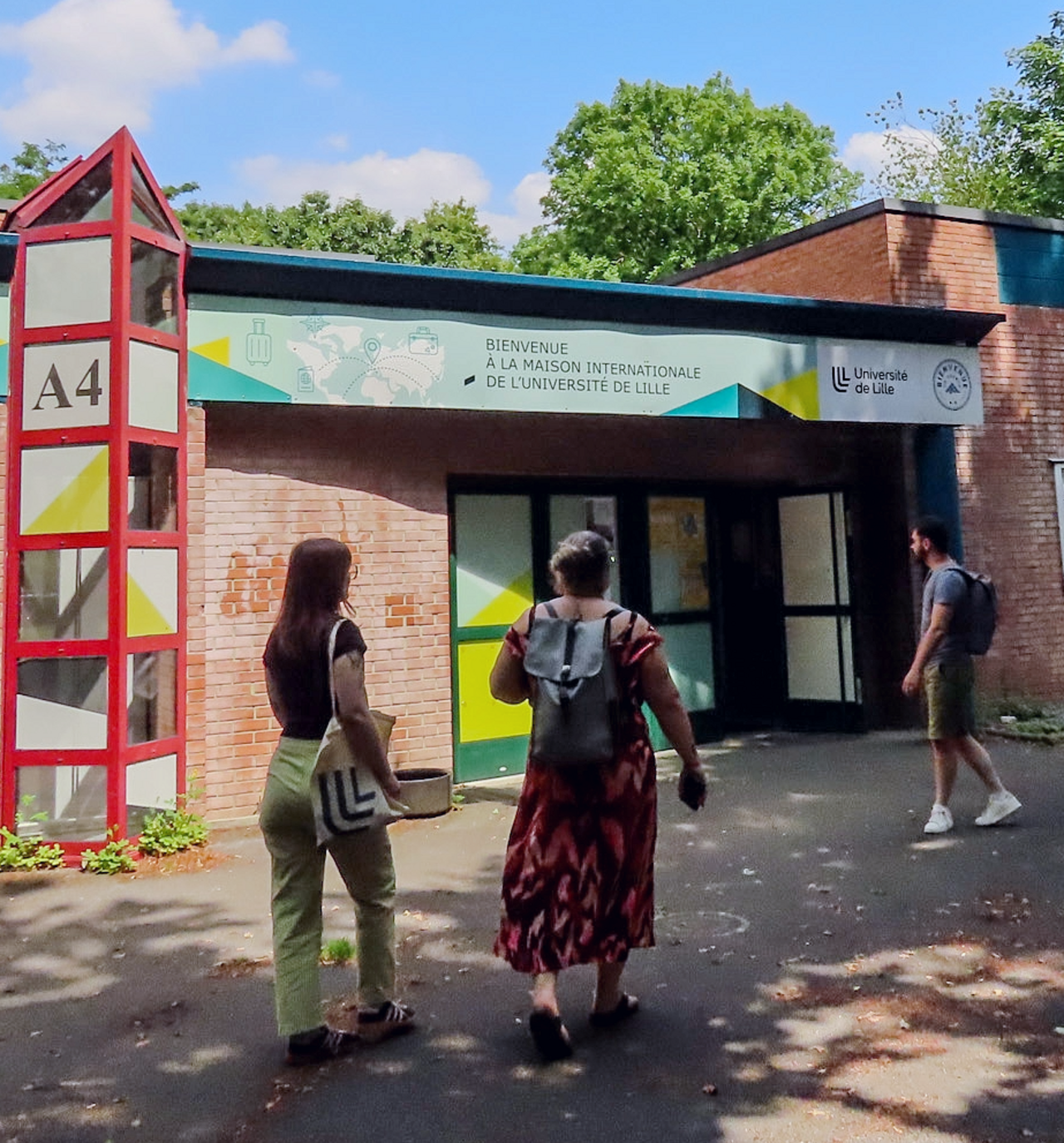 [Translate to EN:] Photo prise devant la Maison Internationale avec 3 étudiants qui rentrent